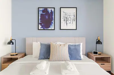 a bedroom with a large white bed with two tables at Silkhaus Gallery Studio at Sky Gardens in DIFC in Dubai