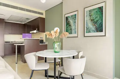 a dining room with a table with chairs and a vase with flowers at Silkhaus Premium 1BDR Stay with DIFC Views in Dubai