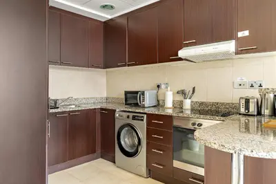 a kitchen with wooden cabinets and a washing machine at Silkhaus Premium 1BDR Stay with DIFC Views in Dubai