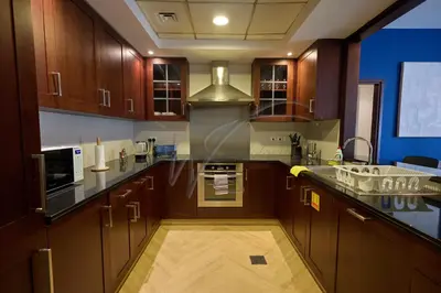 a large kitchen with wooden cabinets and a sink at Full Burj Khalifa and Fountain Views 2BHK Apartment by WS Holiday Homes in Dubai