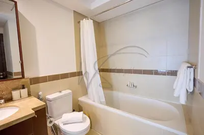 a bathroom with a toilet and a tub and a sink at Full Burj Khalifa and Fountain Views 2BHK Apartment by WS Holiday Homes in Dubai