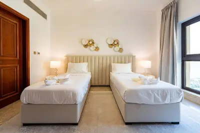 two beds in a room with white walls and windows at TRPS - Fairmont North Residences, Palm Jumeirah - Luxurious 2BR plus Maids, Sea and Harbour View in Dubai