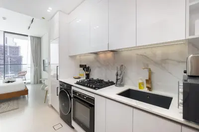 a white kitchen with a stove and a sink at StayShort - Perfect Studio in Binghatti Azure JVC - Sleeps 2 in Dubai
