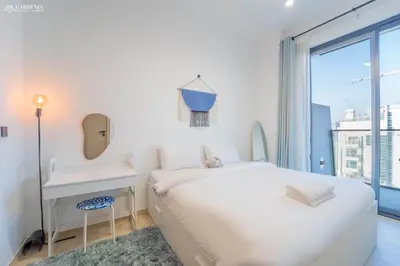 a white bedroom with a large white bed and a window at Modern Brand New 1BR Luxury Apartment With Cozy Interiors In Jumeirah Village Circle in Dubai