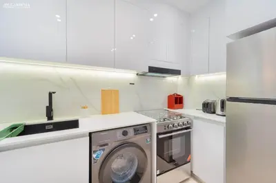 a white kitchen with a washing machine in it at Modern Brand New 1BR Luxury Apartment With Cozy Interiors In Jumeirah Village Circle in Dubai