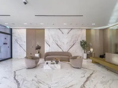 a lobby with a couch and chairs and a marble wall at Modern Brand New 1BR Luxury Apartment With Cozy Interiors In Jumeirah Village Circle in Dubai