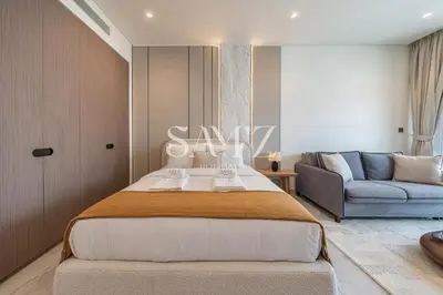 a bedroom with a large bed and a couch at Chic Studio Unit 1808 Peninsula Five in Sabkhah