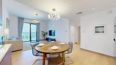 a dining room and living room with a table and chairs at Locations l Upgraded 1 Bedroom l Sea Views, Beach Access l Port de La Mer in Dubai
