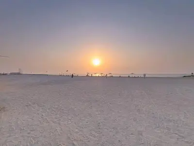 a group of people on the beach at sunset at Locations l Upgraded 1 Bedroom l Sea Views, Beach Access l Port de La Mer in Dubai