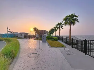 a walkway next to the ocean with palm trees at Locations l Upgraded 1 Bedroom l Sea Views, Beach Access l Port de La Mer in Dubai