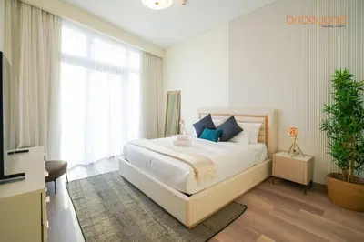 a bedroom with a large white bed with blue pillows at Urban Grandeur at Imperial Avenue in Dubai
