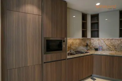 a kitchen with wooden cabinets and a tv on the wall at Urban Grandeur at Imperial Avenue in Dubai