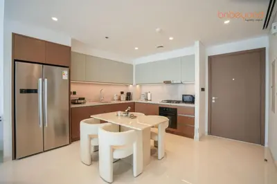 a kitchen with a table and chairs and a refrigerator at Private Beach Access with Luxury Beachfront Lifestyle in Dubai