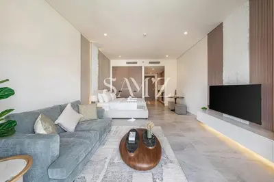 a living room with a gray couch and a tv at Cozy Studio - Unit 1807 - Peninsula Five in Dubai