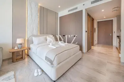 a bedroom with a large white bed and a table at Cozy Studio - Unit 1807 - Peninsula Five in Dubai