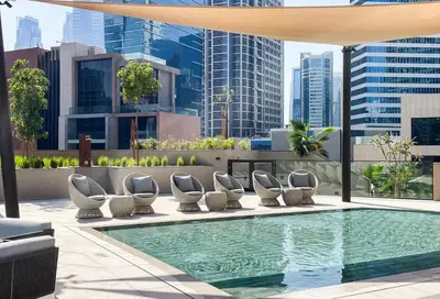 a swimming pool with lounge chairs and a building at Sleek 1BR Gem - Unit 1709 - Peninsula Five in Dubai