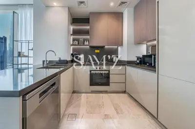 a kitchen with stainless steel appliances and wood cabinets at Sleek 1BR Gem - Unit 1709 - Peninsula Five in Dubai