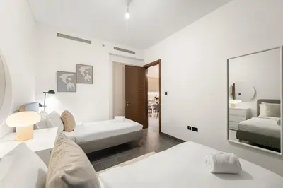 a white living room with a bed and a mirror at FIRST CLASS 2BR Luxury Hideaway in Dubai