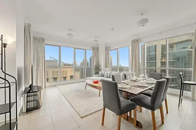 a dining room with a table and chairs and windows at FIRST CLASS 1BR Downtown Luxury in Dubai
