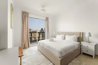 a white bedroom with a bed and a large window at FIRST CLASS 1BR Downtown Luxury in Dubai