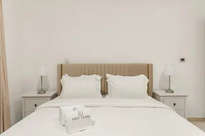 a bed with white sheets and pillows and two lamps at FIRST CLASS 1BR Downtown Luxury in Dubai
