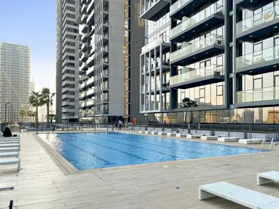 a swimming pool in front of a building with tall buildings at FIRST CLASS 1BR Relaxing Vibes in JVC in Dubai