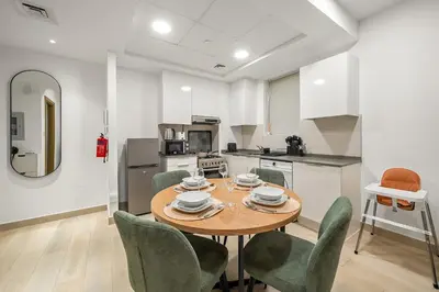 a dining room with a table and chairs and a kitchen at FIRST CLASS 1BR Relaxing Vibes in JVC in Dubai