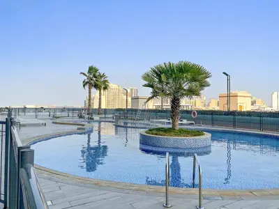 a large swimming pool with a palm tree in it at FIRST CLASS 1BR Relaxing Vibes in JVC in Dubai
