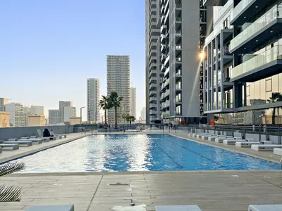 a large swimming pool in a city with tall buildings at FIRST CLASS 1BR Relaxing Vibes in JVC in Dubai