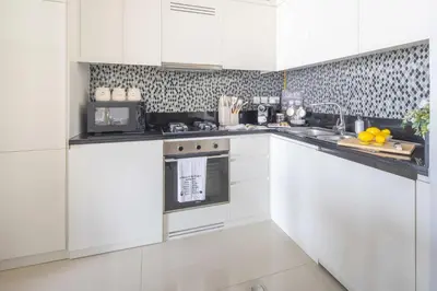 a white kitchen with white cabinets and a sink at Frank Porter - Aykon City 2 Tower C in Dubai