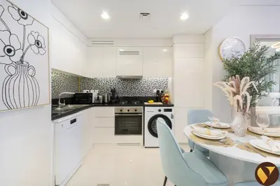 a kitchen with white cabinets and a table and chairs at Vogue Business Bay Aykon City Tower Close to Downtown Burj Khalifa and Dubai Mall, Two Bedroom Apartment with Large Balcony Sea view, Access to all Amenities in Dubai