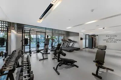 a gym with treadmills and chairs in a room at Modern 1BR with Terrace, Rooftop Pool and PS5 in JVC in Dubai