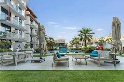 a patio with chairs and umbrellas in front of a building at Modern 1BR with Terrace, Rooftop Pool and PS5 in JVC in Dubai