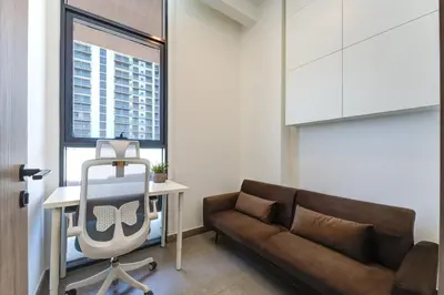 a living room with a couch and a desk at Modern 1BR with Terrace, Rooftop Pool and PS5 in JVC in Dubai