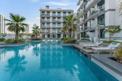 an infinity pool at a hotel with palm trees at Modern 1BR with Terrace, Rooftop Pool and PS5 in JVC in Dubai