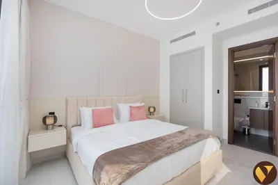 a white bedroom with a large bed with pink pillows at Vogue Al Maktoum City Sobha Hartland The Crest Near to Downtown, Burj Khalifa and Dubai Mall, Three Bedroom plus Kid's room apartment with Balcony and City View, Access to all Amenities in Dubai