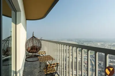 a balcony with two chairs and a view of a city at Vogue Al Maktoum City Sobha Hartland The Crest Near to Downtown, Burj Khalifa and Dubai Mall, Three Bedroom plus Kid's room apartment with Balcony and City View, Access to all Amenities in Dubai