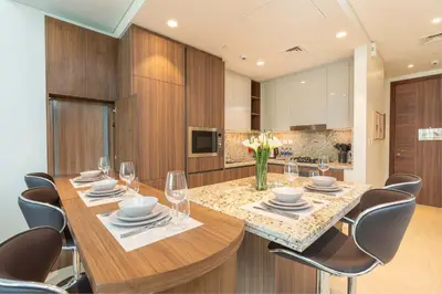 a dining room with a wooden table and chairs at PVH - 1BR with Burj Khalifa View - Imperial Avenue in Dubai