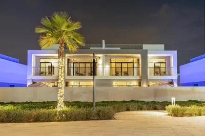 a building with a palm tree in front of it at Luxe 6BR Semi-Detached Villa Steps from the Lagoon in Dubai
