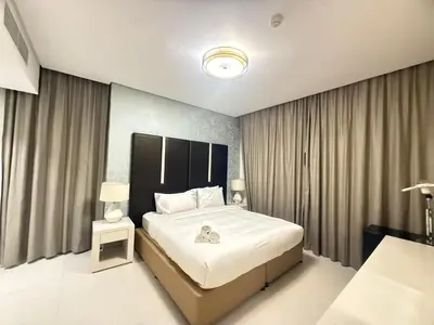 a bedroom with a bed and a lamp and curtains at Wecation- Chic 2BR Damac Maison Cour Jardin Business Bay in Dubai