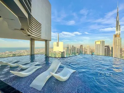a pool on the roof of a building with white chairs at Luxury 2B Burj Khalifa NYE Views, 5-Star Amenities in Dubai