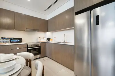 a kitchen with wooden cabinets and a stainless steel refrigerator at Full Burj Khalifa And Fountains View Exclusive 2BR Luxury Apartment In The Heart Of Downtown Dubai in Dubai