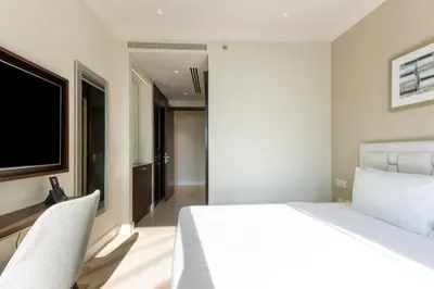 a bedroom with a white bed and a flat screen tv at Unobstructed Burj Fountain View Near Dubai Mall in Dubai