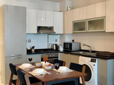 a kitchen with a table with chairs and a washer at Burj View 1BHK near Down Town - Panoramic Balcony View -Pool and Gym in Dubai