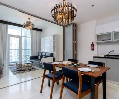 a kitchen and living room with a table and chairs at Burj View 1BHK near Down Town - Panoramic Balcony View -Pool and Gym in Dubai