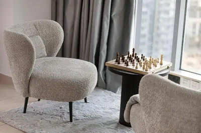 a chair and chessboard on a table next to a window at Restay Homes at The Residences Tower 1 - Full Burj Views from all apartments in Dubai