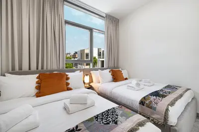 two beds in a room with a large window at Upscale 4BR Villa, Bali Pool, Resort Escape in Dubai