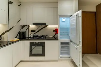 a kitchen with white cabinets and an open refrigerator at 1BR in Trillionaire Residences by Binghatti with canal view in Dubai