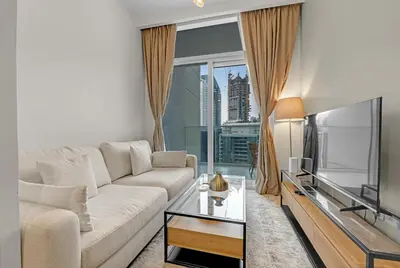 a living room with a white couch and a television at Waves - Modern City Escape 1BR Apt With Balcony in Dubai