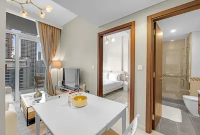 a living room with a white table and a bathroom at Waves - Modern City Escape 1BR Apt With Balcony in Dubai
